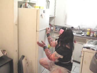 Sissy Maid Cleaning In Bondage - Sissy chastity is bound and gagged, chained up, and must clean out the broken refrigerator while sissified, bound, gagged, and in chastity. She even waters the floor!